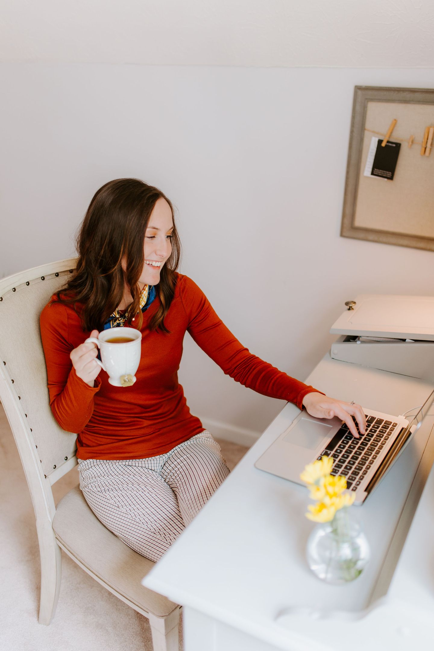 woman smiling on computer with tea